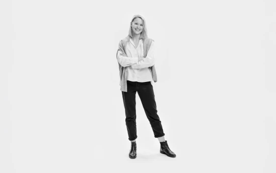 Woman with arms folded in white shirt black trousers.